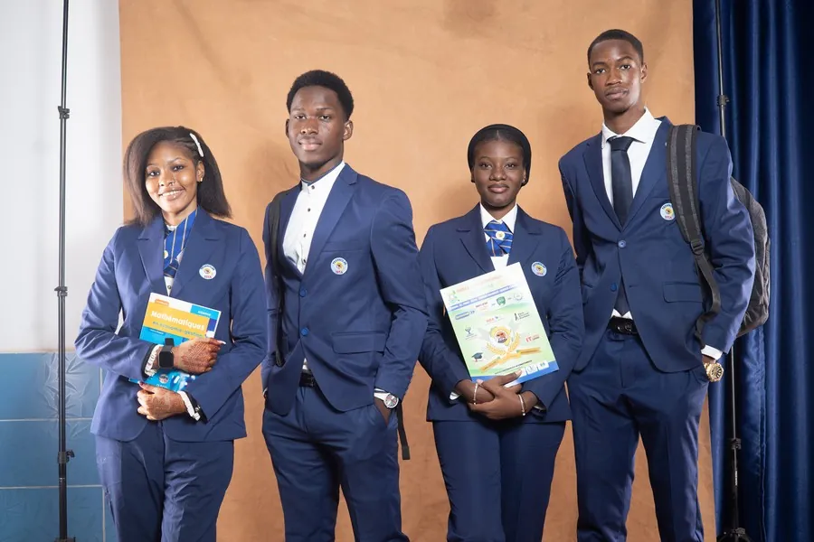 Quatre étudiants en blazer bleu de l’établissement, documents à la main.