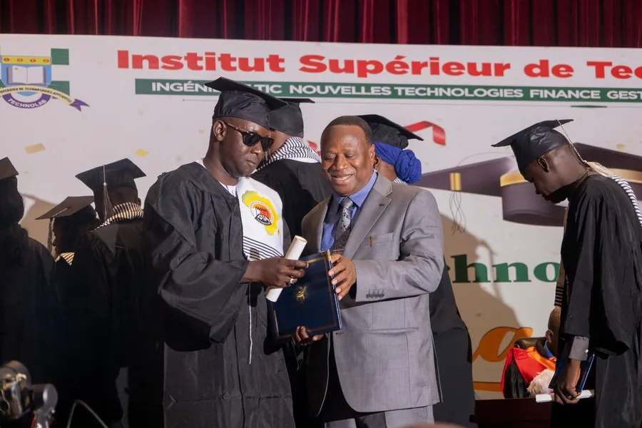 Remise d’un diplôme par un responsable de l’établissement, devant le panneau de l’Institut Supérieur de Technologies Appliquées.