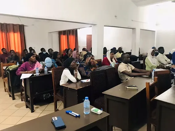 Étudiants suivant un cours, installés à des tables de travail dans une salle équipée.